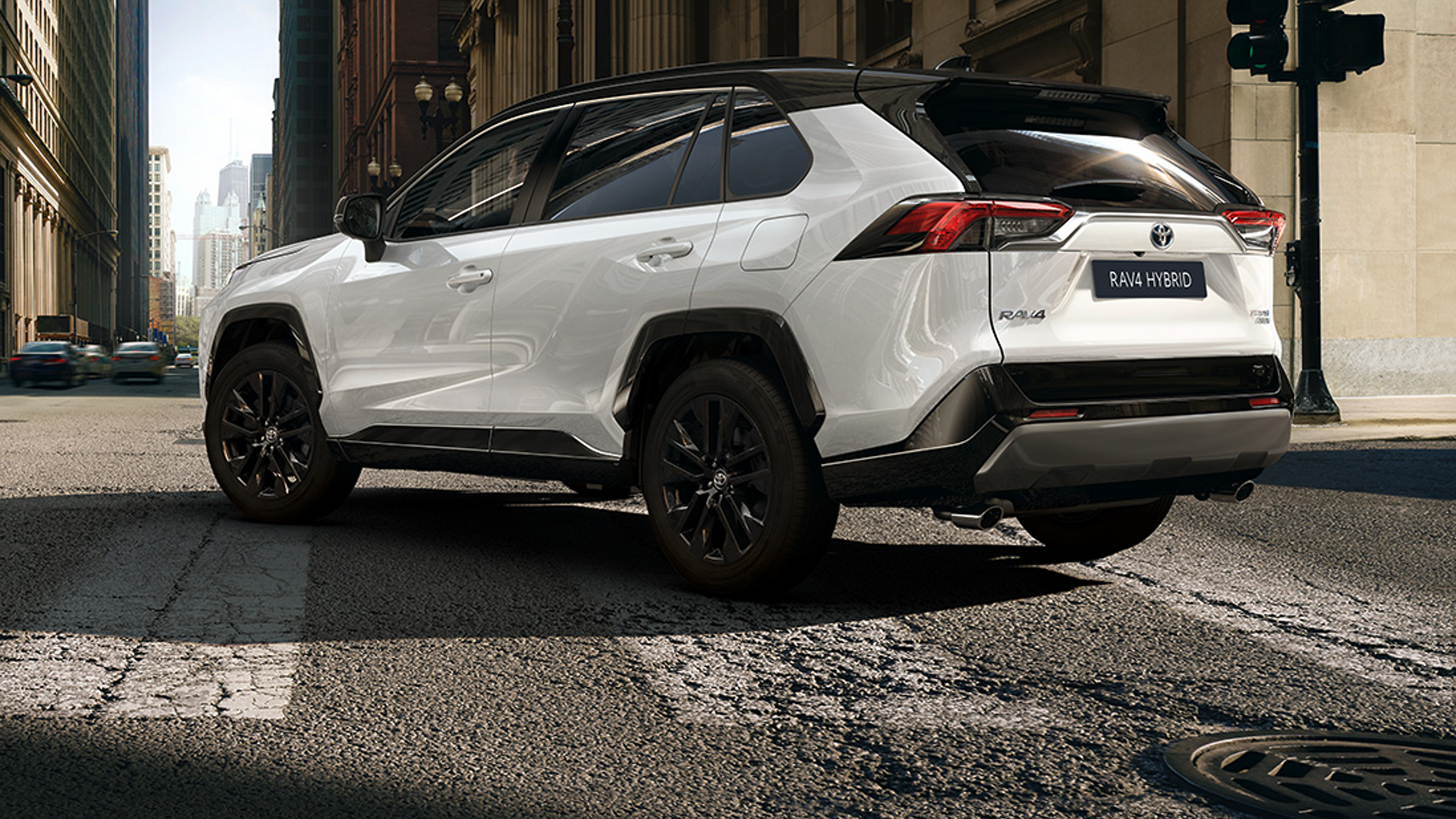 Il RAV4 percorre una strada di città illuminata dal sole