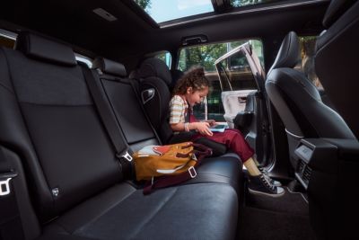 Girl sitting in back seat of Toyota car