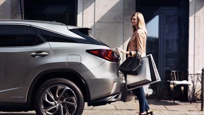 two people standing next to a Lexus UX 300e