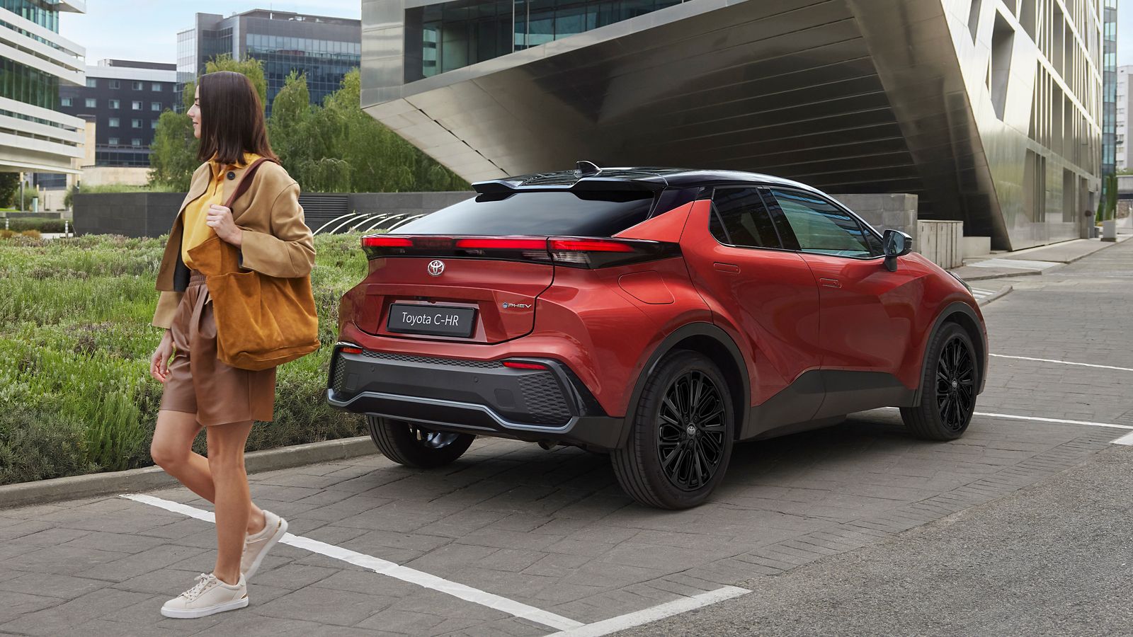 İçinde valizler olan Toyota C-HR Hybrid bagajını kapatan bir adam