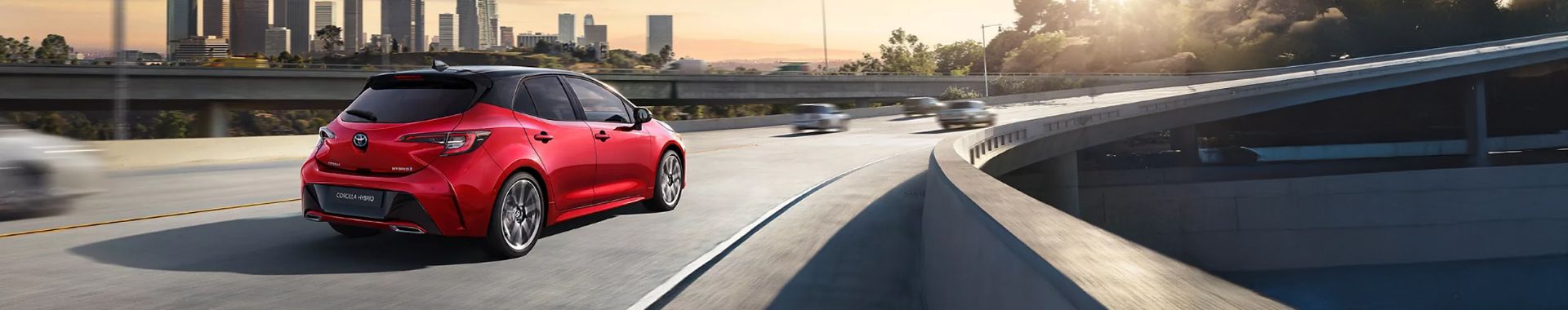 Červený vůz Toyota Corolla Hybrid jede po dálnici.