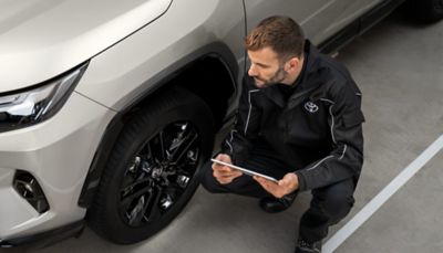 Ein Toyota-Mechaniker überprüft in einem Parkhaus mithilfe eines Tablets den Zustand der Reifen und Felgen eines Autos