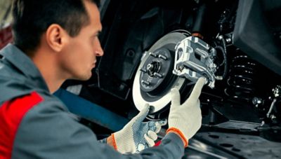 Ein Toyota-Mechaniker wechselt bei der Fahrzeugwartung in einer Werkstatt die Bremsscheibe und den Bremssattel aus