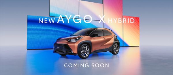 Toyota Aygo X Hybrid in metallic gold with bi-tone black bonnet and roof in a vibrant blue studio setting.