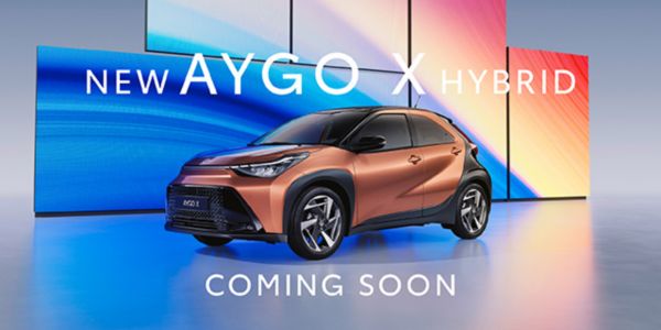 Toyota Aygo X Hybrid in metallic gold with bi-tone black bonnet and roof in a vibrant blue studio setting.