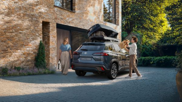 Žena s mužem vyndávají nákupy ze střešního boxu nového vozu Corolla Cross