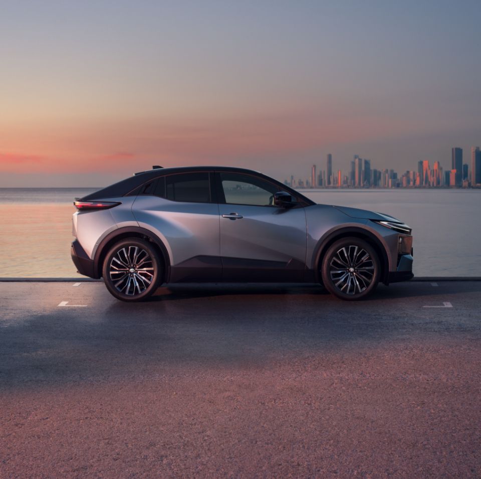 Toyota C-HR na tle miasta po drugiej stronie wody w świetle zachodzącego słońca