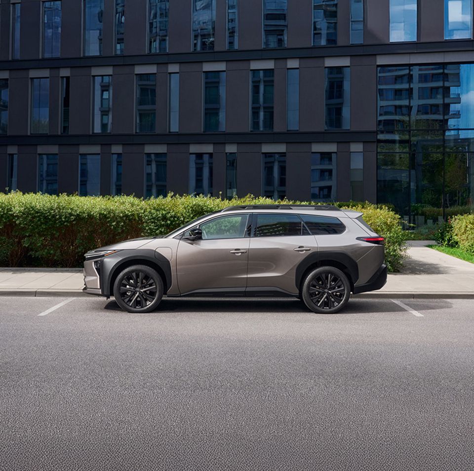 Toyota BZ4X Touringról sövény és magas épület előtt