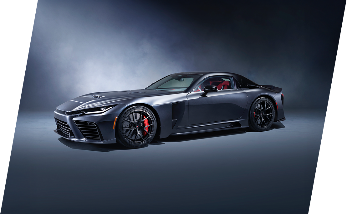 Egy sötétkék Toyota Gazoo Racing versenyautó, fehér és piros mintákkal, kivilágított fényszórókkal, egy garázsban állva.