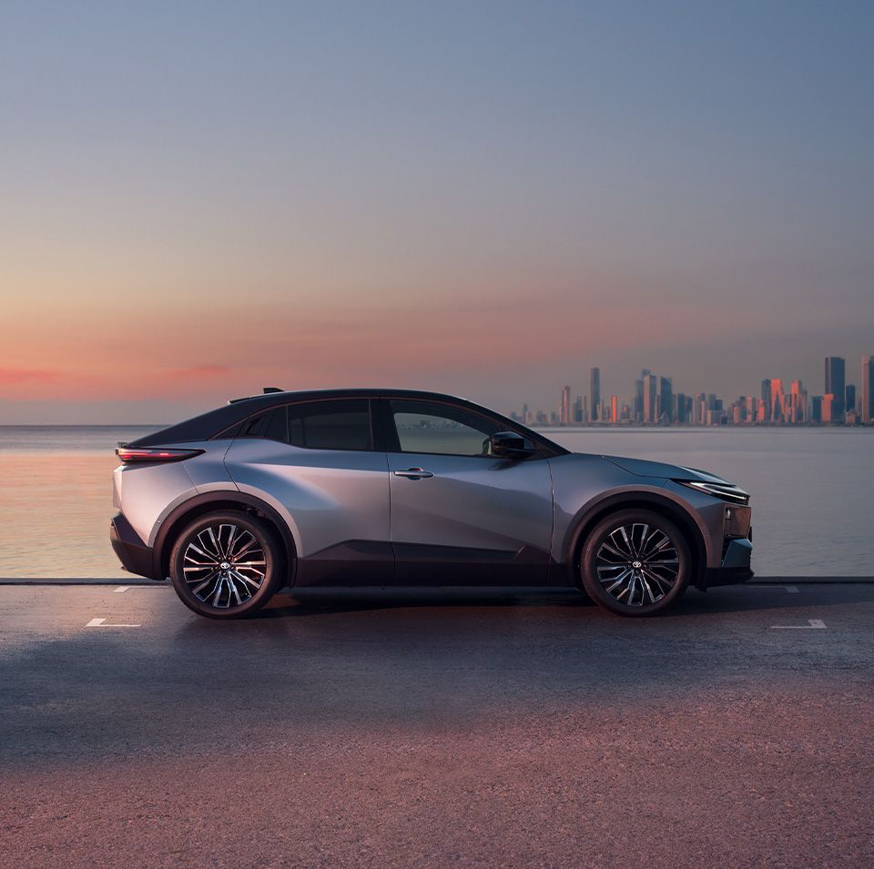 Toyota C-HR na tle miasta po drugiej stronie wody w świetle zachodzącego słońca