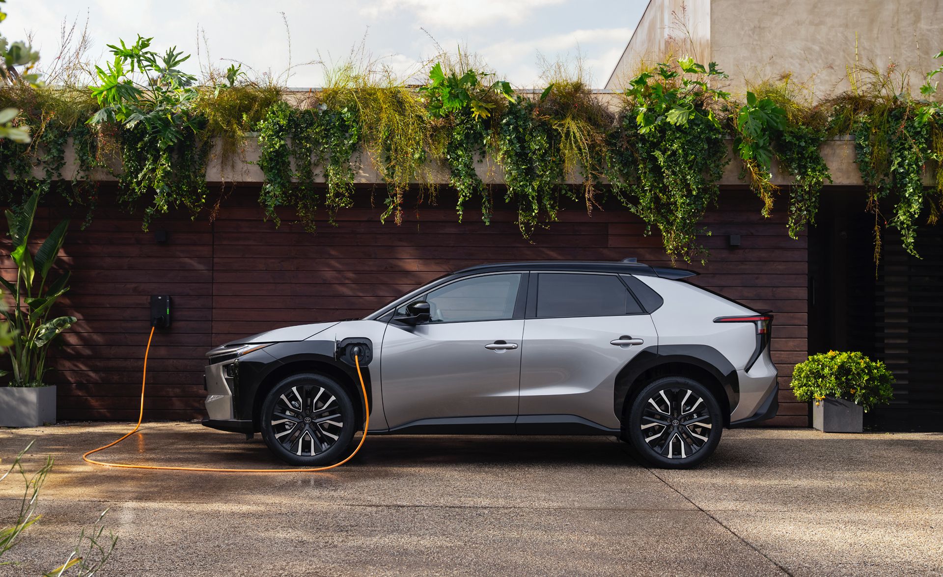 Toyota bZ4X növényekkel benőtt fal előtt.