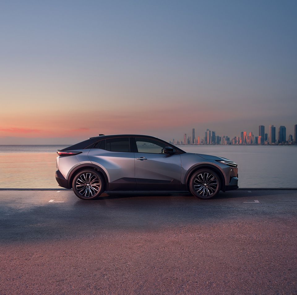 Szara Toyota C-HR+ na tle morza w świetle zachodzącego słońca