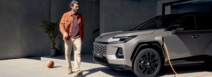 Mężczyzna w garażu obok ładującej się Toyoty RAV4 Plug-in Hybrid