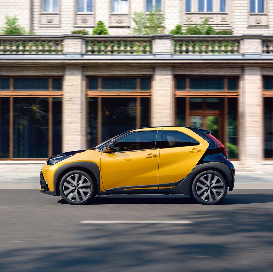 Žlutá Toyota Aygo X na pozadí monumentální budovy