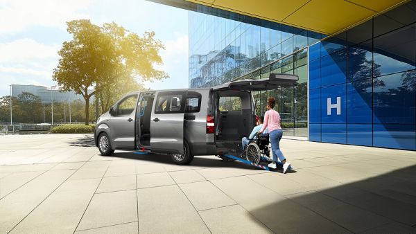 Person hilft einem Rollstuhlfahrer in einen Proace Verso hineinzufahren.