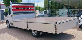 Bílý užitkový vůz Toyota Proace s otevřenou nákladovou plošinou, pohled zepředu.