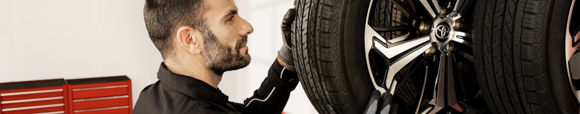 Mechanik kontroluje a montuje kolo s pneumatikou na vozidle Toyota v autoservisu.