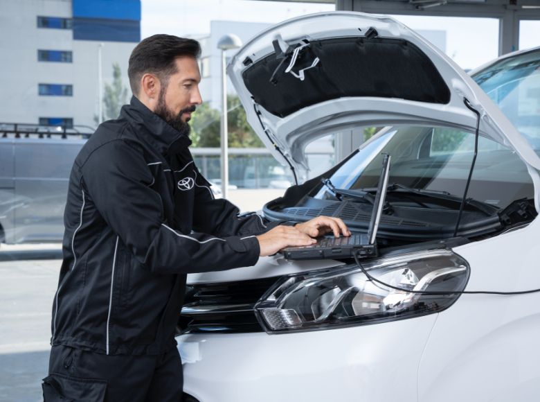 Mechanik kontroluje hybridní auto Toyotu pomocí laptopu.