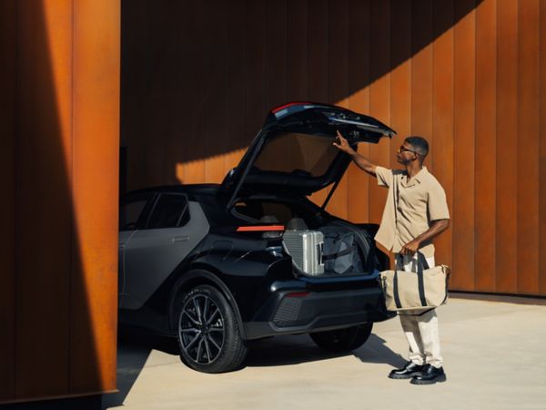 in Mann lädt seine Reisetaschen in den Kofferraum eines schwarzen Autos und verdeutlicht so die flexible Nutzung und den steuerlichen Sachbezug von Firmenwagen in Österreich.