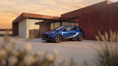 Ein blauer Toyota C-HR steht vor einem modernen Wohnhaus in zeitgemäßer Architektur.