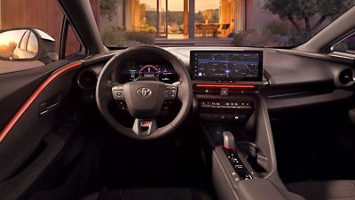 Innenraum des Toyota C-HR mit Lenkrad, digitalem Kombiinstrument und großem mittigem Touchscreen, moderne Armaturenbrettgestaltung mit roten Akzenten