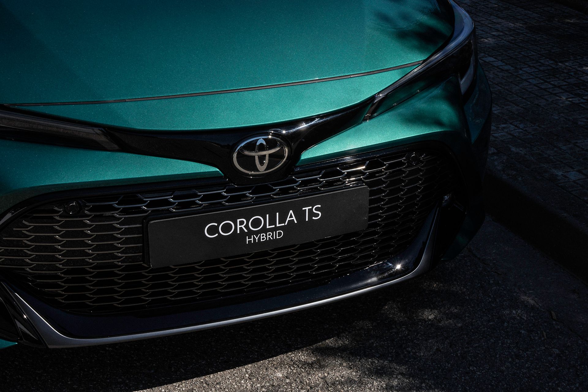 Woman biking by Toyota Corolla Touring Sports parked