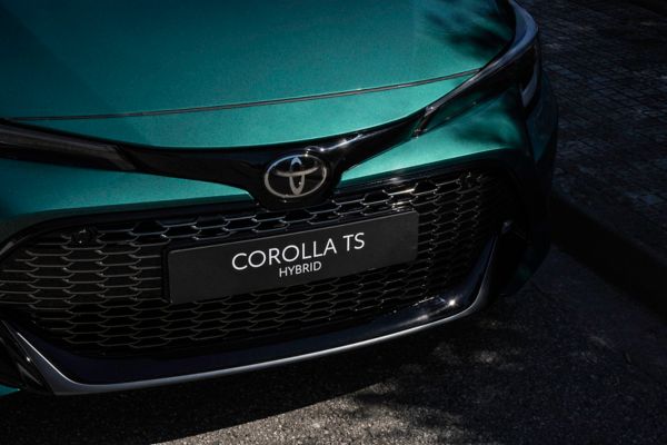 Woman biking by Toyota Corolla Touring Sports parked