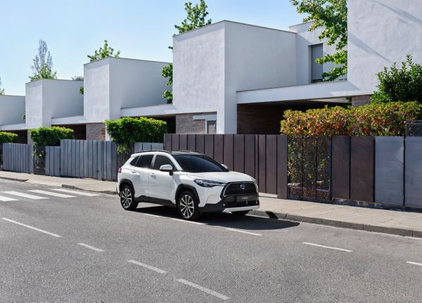 Weißer SUV steht am Straßenrand neben einer Häuserreihe