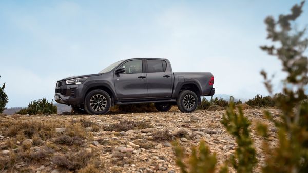 Ein robuster grauer Toyota Pick-up-Truck, der auf felsigem Gelände geparkt ist und vor dem Hintergrund eines klaren Himmels seine Geländetauglichkeit unter Beweis stellt.