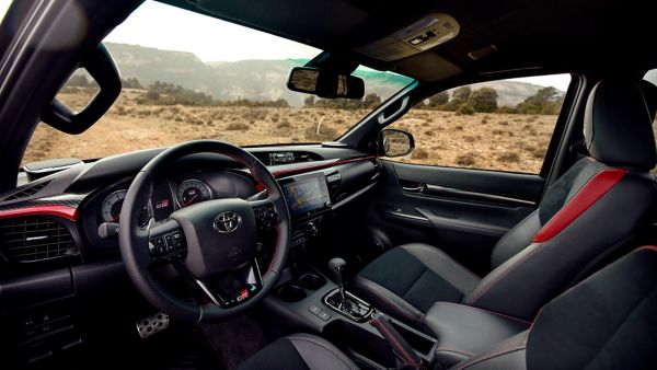 Innenraum des Toyota Hilux im Frontbereich, mit dunklen Sitzen und roten Akzenten