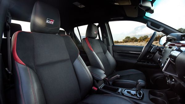 Innenraum des Toyota Hilux mit dunklen Sitzen und roten Ziernähten