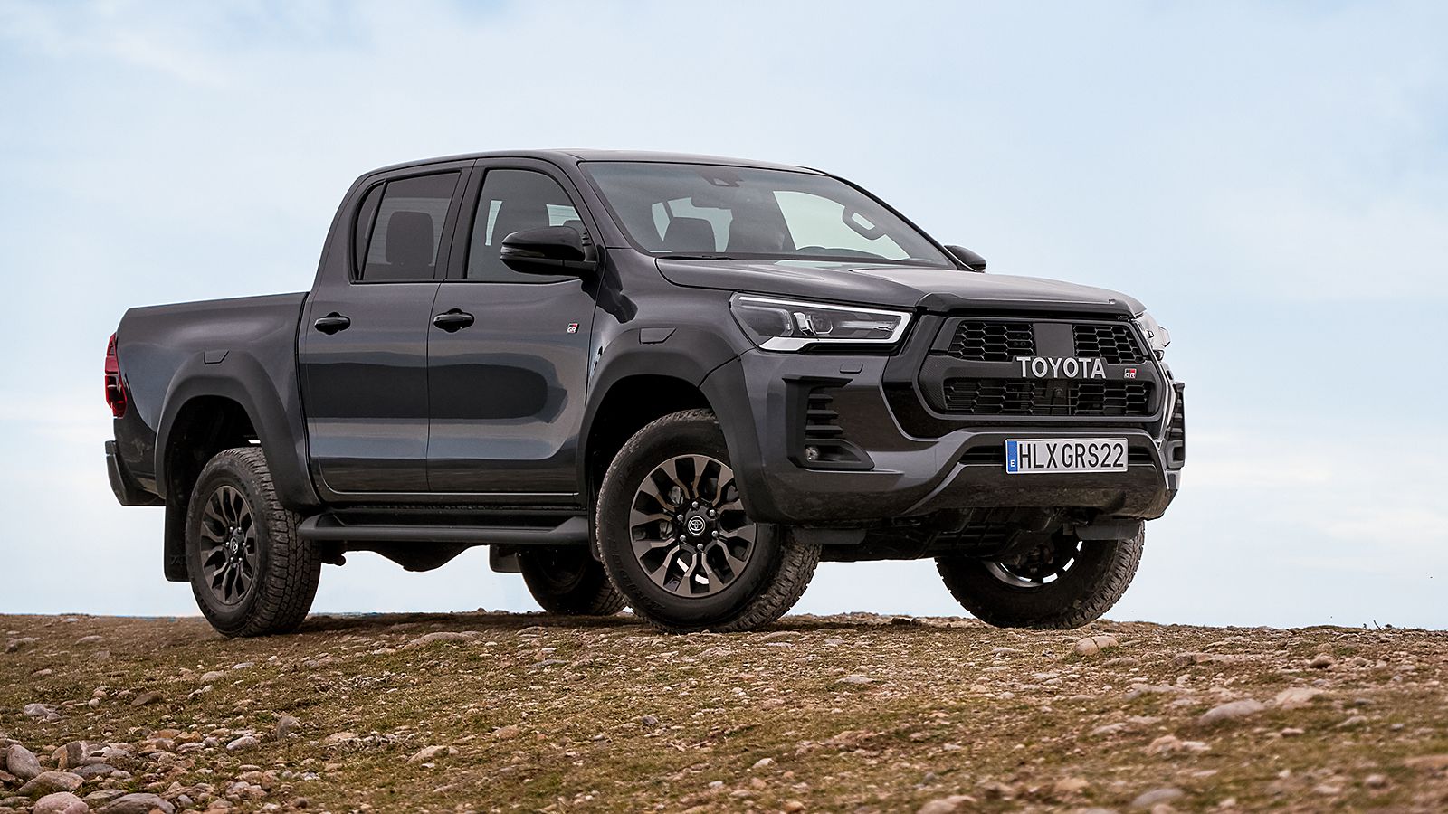 Grauer Toyota Hilux steht seitlich auf einem Hügel