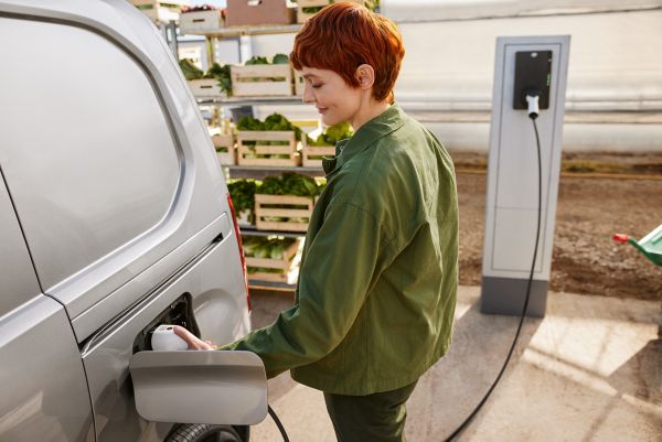 Person steckt einen Stecker einer Ladesäule in die Buchse eines Autos