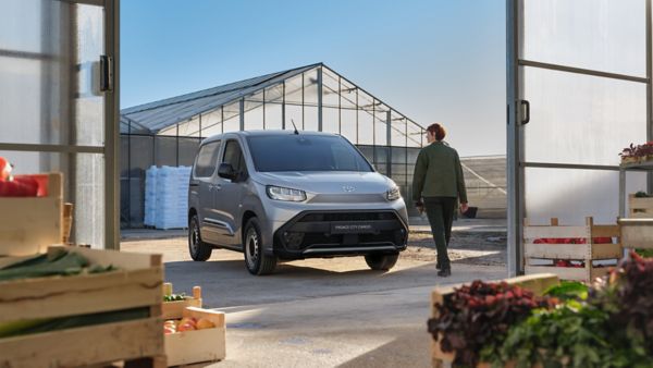 Sera önünde Toyota Proace City Cargo ön görünümü ve bir kadın