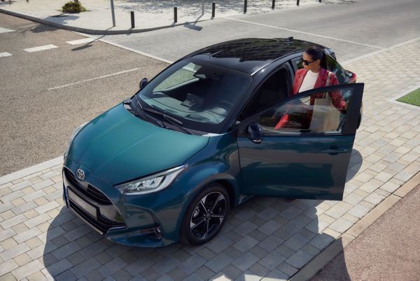 Vrouw stapt ontspannen in haar Toyota Yaris