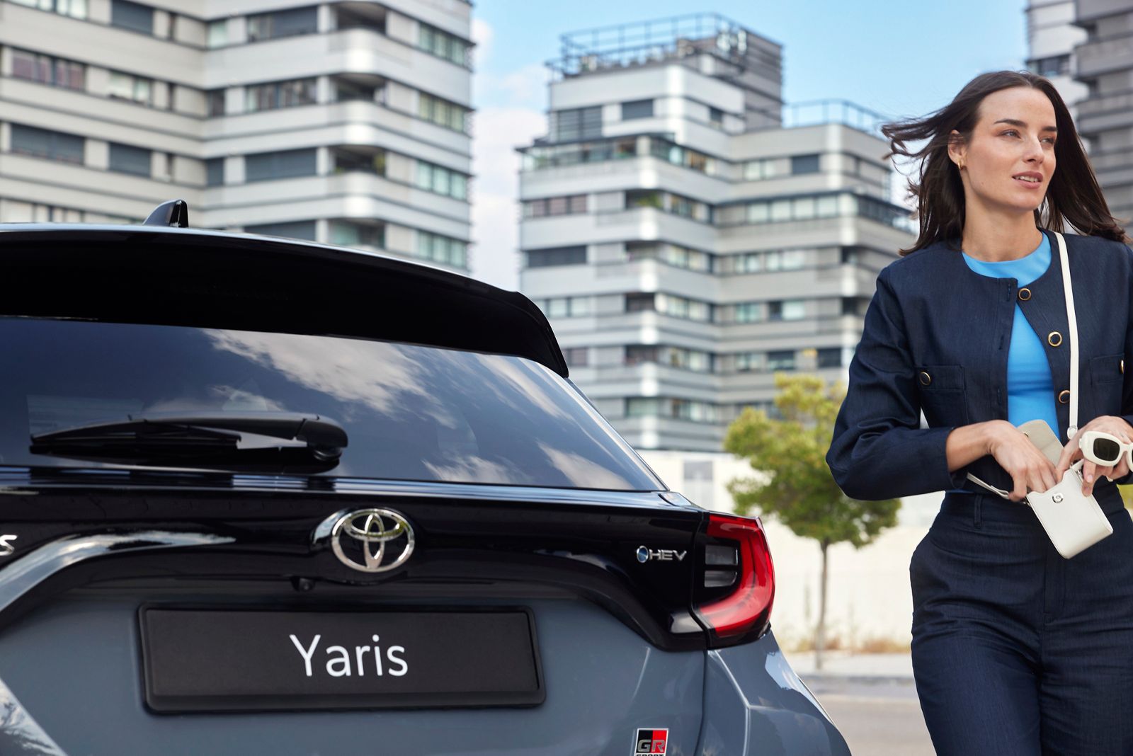 Una donna cammina verso la sua Yaris e, mentre si avvicina, usa il suo smartphone per aprire la vettura. 