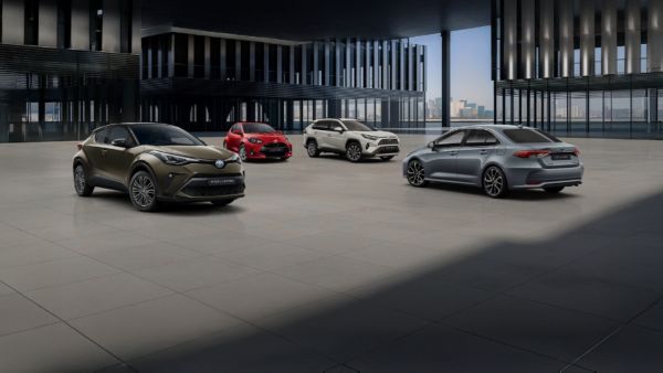 Nowoczesny salon Toyoty z czterema modelami: Toyota C-HR, Yaris, RAV4 i Corolla na tle panoramicznych okien z widokiem na miasto