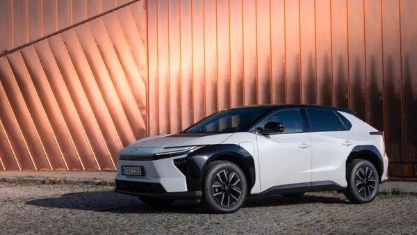 Toyota bZ4X – elektryczny SUV zaparkowany na kostce brukowej przed nowoczesną ścianą z miedzianych paneli