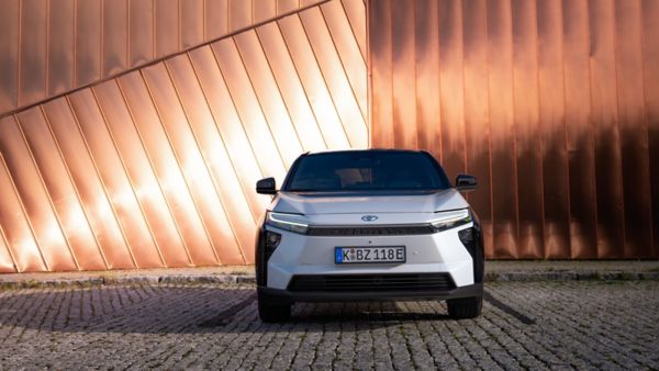 Toyota bZ4X – elektryczny SUV zaparkowany na kostce brukowej przed nowoczesną ścianą z miedzianych paneli