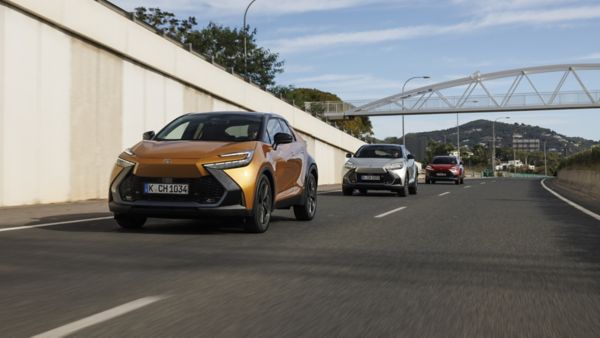 Trzy Toyoty C-HR podążające dwupasmową drogą