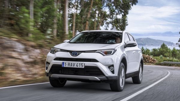Biała Toyota RAV4 podczas jazdy po drodze między drzewami