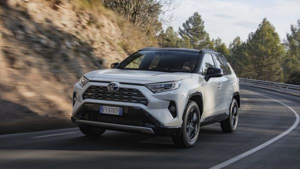 Zjęcie białej Toyoty RAV4 podczas poruszania po drodze na tle drzew