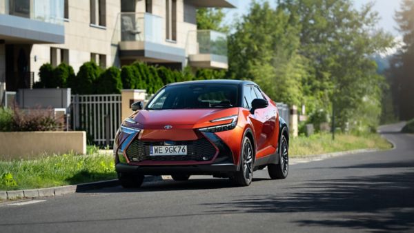 Nowa Toyota C-HR w czerwonym kolorze zaparkowana obok domu