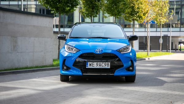 Przód Toyoty Yaris na tle drzew i biurowca