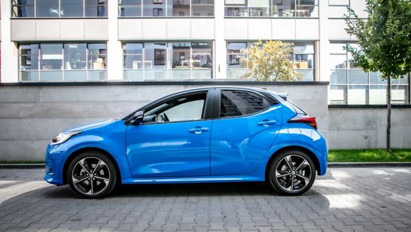 Niebieska Toyota YAris zaparkowana na tle granitowego muru
