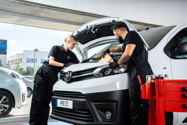 Two mechanics working together on a vehicle.