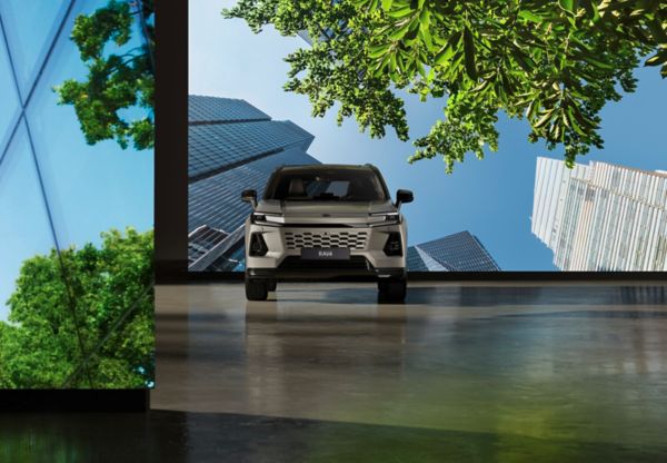 RAV4 hybride rechargeable garé devant un écran montrant des gratte-ciels et des arbres