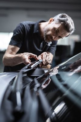 Nahaufnahme eines Mechanikers in einer Werkstatt, der einen Scheibenwischer installiert 