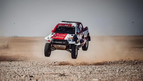 Rallye-Fahrzeug mit Toyota Logo und einer Folierung mit Sponsoren springt in der Luft