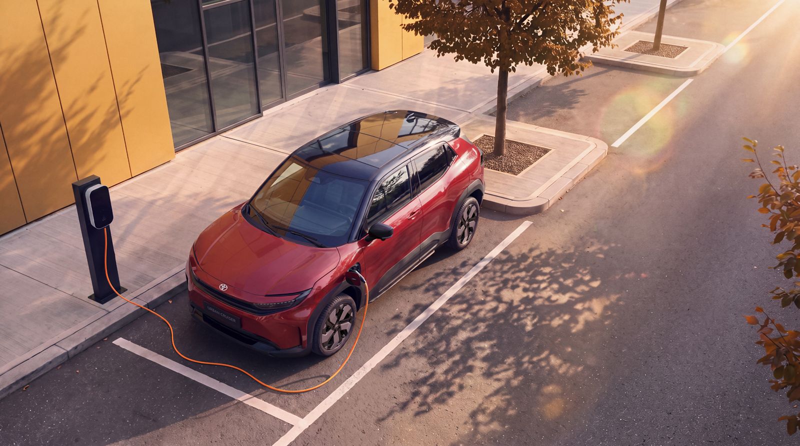 Ein Toyota Urban Cruiser steht im Seitenprofil vor einem modernen Gebäude mit gelber Fassade.